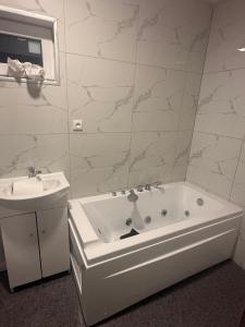 a white bathroom with a tub and a sink at Bernotiškių Hotel & Dining  +5 photos
