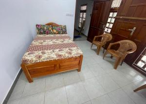 a bedroom with a wooden bed and two chairs at Moringa Villa in Maruthanamadam