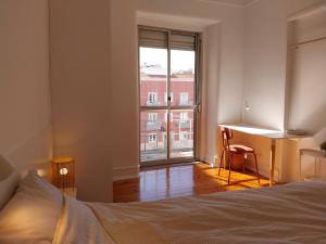 a bedroom with a bed and a desk and a window at Stylish Cacilhas rooms near the ferry to central Lisbon in Almada