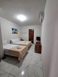 Pousada Recanto do Cajueiro في ساو جوزيه دا كوروا غراندي: غرفة نوم بها سريرين وتلفزيون بداخلها