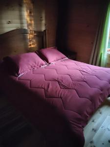 1 cama con edredón y almohadas rosas en Cabañas mountain Native forest, en Voipire