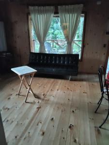 Una sala de estar con un sofá negro y una mesa. en Cabañas mountain Native forest, en Voipire