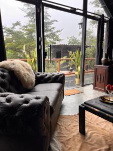 um sofá de couro numa sala de estar com uma grande janela em ConstelacaodaChapada em Ibicoara mais 1 fotografia