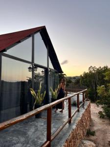 uma mulher sentada no convés de uma casa em ConstelacaodaChapada em Ibicoara