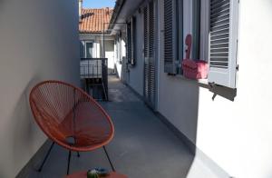 Thea- Duomo Centro storico في مونزا: كرسي أحمر موضوع على شرفة بجوار مبنى