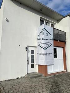 a white building with a sign on the side of it at Work & Travel Lodge Münsingen in Münsingen
