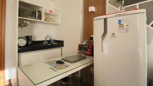 eine Küche mit einem weißen Kühlschrank und einem Tisch in der Unterkunft Flat com Piscina, Academia e Sauna em Aguas Claras in Águas Claras