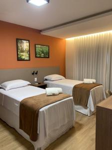 Dos camas en una habitación con paredes naranjas. en Belém Forest Inn, en Belém