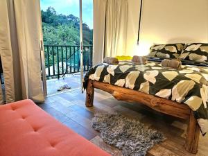 Jardin De Poas Hotel & Nature Resort في Poás: غرفة نوم بها سرير وأريكة وشرفة +126 صورة