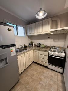 a kitchen with white cabinets and a stove and a refrigerator at Capibara 7 - Alborada in Corrientes