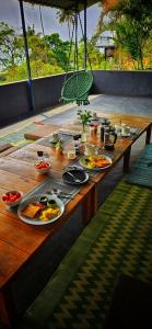 un tavolo di legno con piatti di cibo sopra di Petit Ana Beach Retreat a Varkala