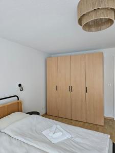 a bedroom with a white bed and wooden cabinets at Summit View Apartment in Spiez