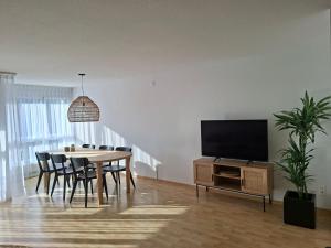 a dining room with a table and a flat screen tv at Summit View Apartment in Spiez