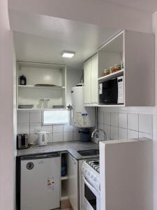 Una cocina con electrodomésticos y gabinetes blancos. en Loft - Zona hospitales - Familias!, en Rosario