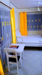 a room with a table and a bed with yellow curtains at Phee home in Mombasa