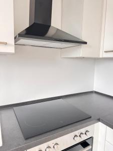 Comfort Apartment في Denkendorf: مطبخ بخزائن بيضاء وفرن موقد +صورتان