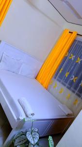 a small bed in a room with yellow rails at Phee home in Mombasa +2 photos