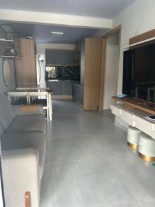 a large kitchen with a couch and a television at Casa com piscina in Tramandaí