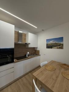 a kitchen with white cabinets and a wooden table at Inn Puglia Guest House 2 in Acquaviva delle Fonti