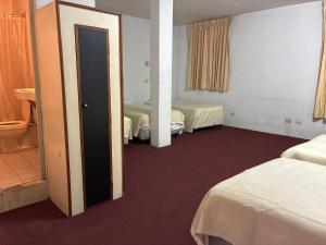 a hotel room with two beds and a mirror at Hotel Los Proceres in La Aurora