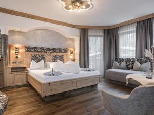 Un dormitorio con una cama grande y un sofá. en Hotel Alpenjuwel 4 Sterne Superior, en Tux 57 fotos más