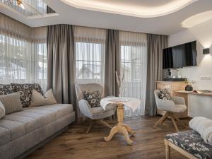 Una sala de estar con un sofá y sillas y una mesa. en Hotel Alpenjuwel 4 Sterne Superior, en Tux