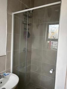 een douche met een glazen deur naast een wastafel bij Manor Rentals in Potchefstroom