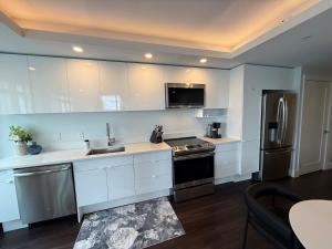 eine Küche mit weißen Schränken und Geräten aus Edelstahl in der Unterkunft Waterfront 1 BR corner unit - 6 appliances & gym in Halifax