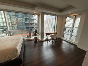 ein Schlafzimmer mit Bett, Schreibtisch und Fenstern in der Unterkunft Waterfront 1 BR corner unit - 6 appliances & gym in Halifax