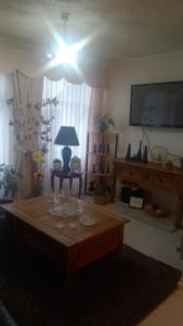 a living room with a table and a tv at Apartamento Costanera in Punta Arenas