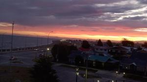 a view of a city with a sunset in the background at Apartamento Costanera in Punta Arenas