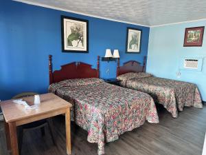 due letti in una camera d'albergo con pareti blu di Riverside inn motel a Plymouth