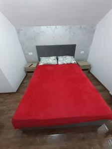a red bed with a red blanket in a room at Casa de vacanta Gea Transalpina in Şugag