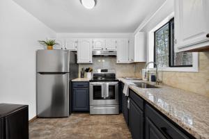 a kitchen with white cabinets and a stainless steel refrigerator at Private Pocono Retreat with Hot Tub and Fire Pit in Thornhurst