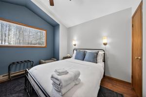 a bedroom with a bed with blue walls and a window at Private Pocono Retreat with Hot Tub and Fire Pit in Thornhurst