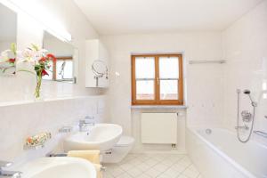 a white bathroom with a sink and a toilet and a tub at Ferienwohnung Kühn in Oberstdorf
