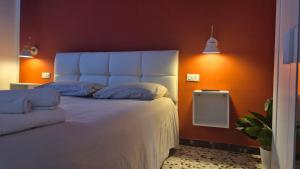 a bedroom with a white bed with an orange wall at La Casa di Athina in Celano