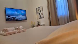 a bedroom with a bed with towels and a flat screen tv at La Casa di Athina in Celano