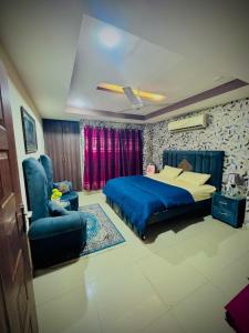 The Diplomat Suites Bahria Town في روالبندي: غرفة نوم بها سرير أزرق وكرسي