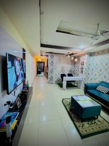 The Diplomat Suites Bahria Town في روالبندي: غرفة معيشة مع أريكة وتلفزيون