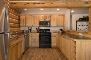 a kitchen with wooden cabinets and a black stove top oven at Powder Ridge Cabin - 9A Red Cloud in Big Sky
