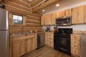 a kitchen with wooden cabinets and a black appliances at Powder Ridge Cabin - 9A Red Cloud in Big Sky +48 photos