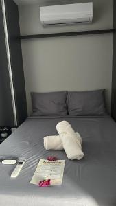 Aloha flats في ماريشال ديودورو: كومة من المناشف على سرير مع كتيب