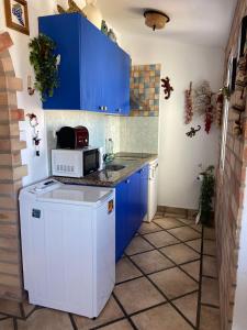a small kitchen with blue cabinets and a microwave at Casa Tesoreta in Cala en Forcat +7 photos