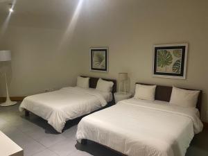 キャバレテにある2 Bedroom Apartmentの白いシーツが敷かれた部屋にベッドが2つ