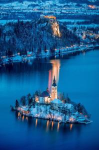 an island in the middle of a lake at night at Lake Bled Apartment Zerovec in Bled +8 photos