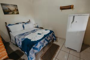a small bedroom with a bed and a refrigerator at Pousada Casa do Cerrado - Alto Paraíso de Goiás in Alto Paraíso de Goiás