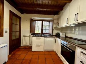 Una cocina con gabinetes blancos y piso de baldosas. en "Casa Bardales", en Alles 34 fotos más