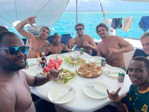 a group of men sitting around a table eating food at Sujees surf stay, cloudbreak in Nadi