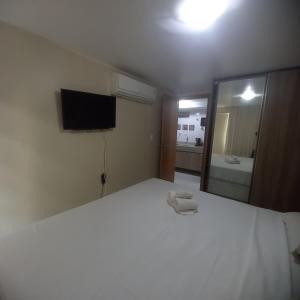 Un dormitorio con una gran cama blanca y un espejo. en Israel Flat Tambaú - 213, en João Pessoa